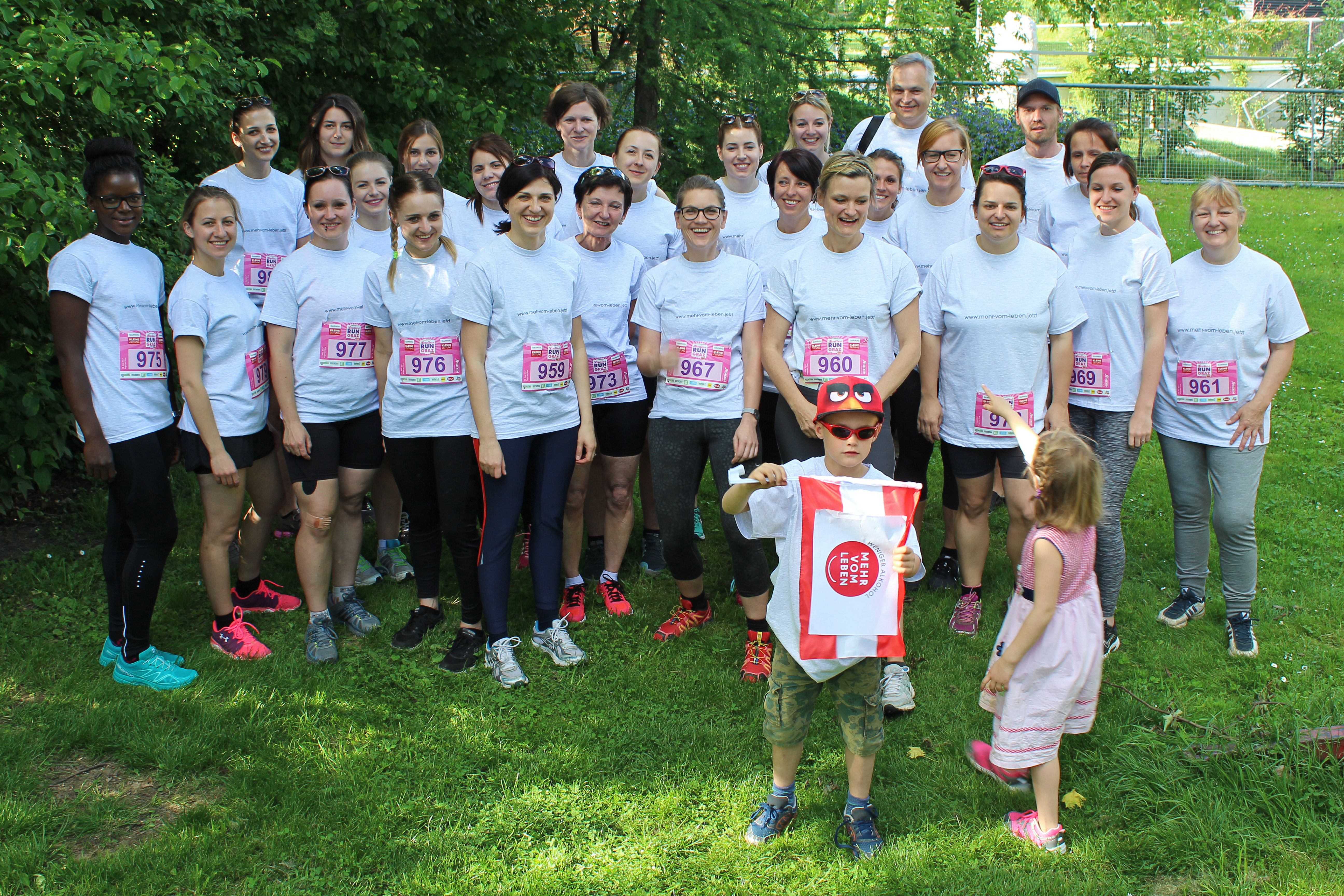 Eine Gruppenfoto von Personen, mehrheitlich Frauen, im Marathon Trikot auf einer Wiese. 