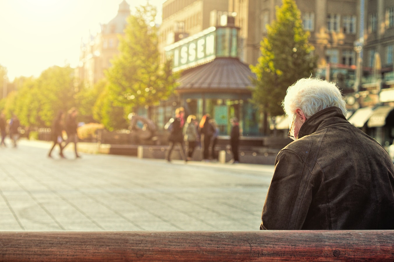 Älterer Mann auf einer Bank an einem Stadtplatz