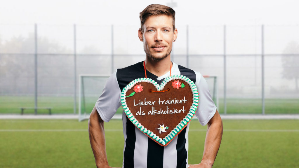 Ein Fußballspieler hat ein Lebkuchenherz mit der Aufschrift "Lieber trainiert als alkoholisiert" umgehängt.