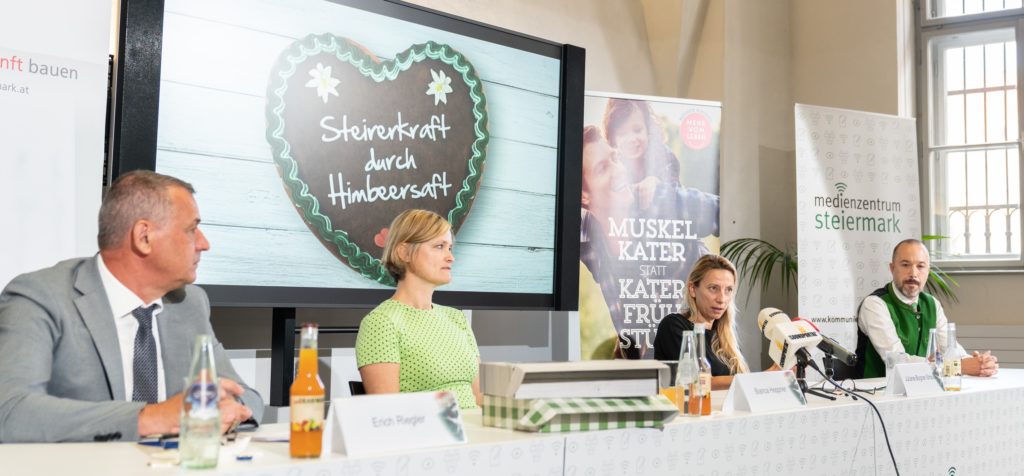 Die Pressekonferenz von der initiative "Mehr vom Leben". Zu sehen ist eine Projektion im Hintergrund. Davor sitzen zwei Frauen und zwei Männer mittleren Alters nebeneinander an einem langen Tisch