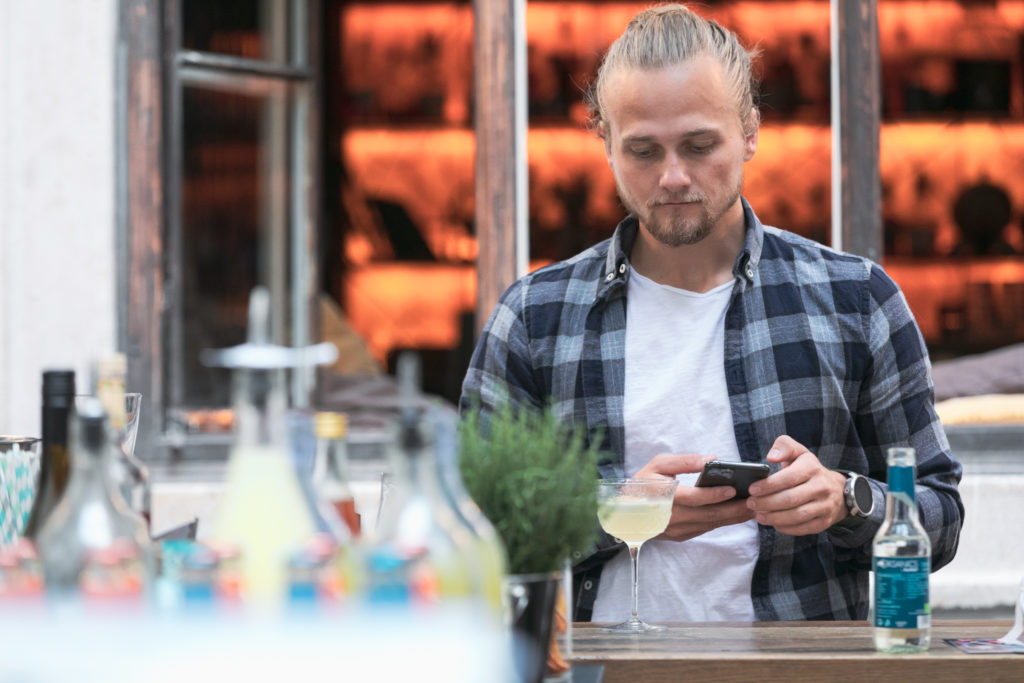 Mann mittleren Alters mit einem Glas und Handy