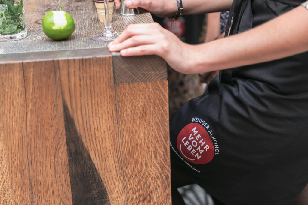 Eine Person mittleren Alters sitzt an einem Tisch, daneben eine teils geschälte Limette   