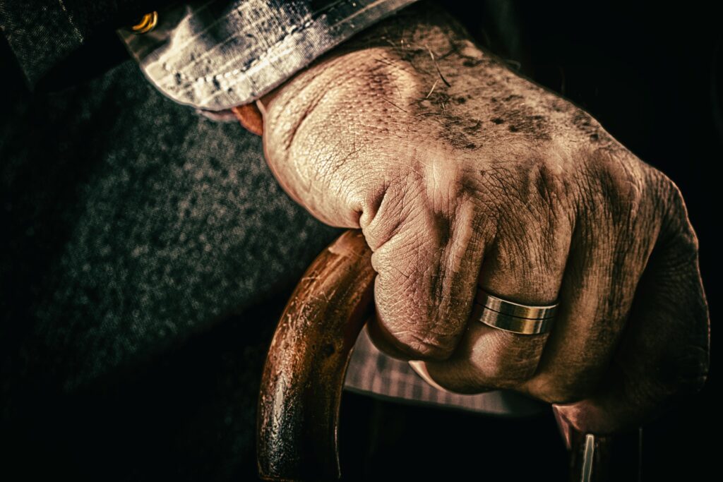 Eine Hand eines alten Mannes hält einen Gehstock