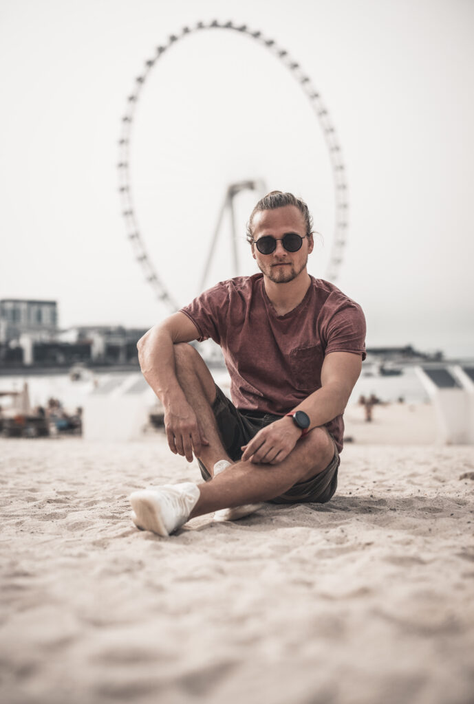 Foto von einem Mann frühen Alters, sitzend im Sand