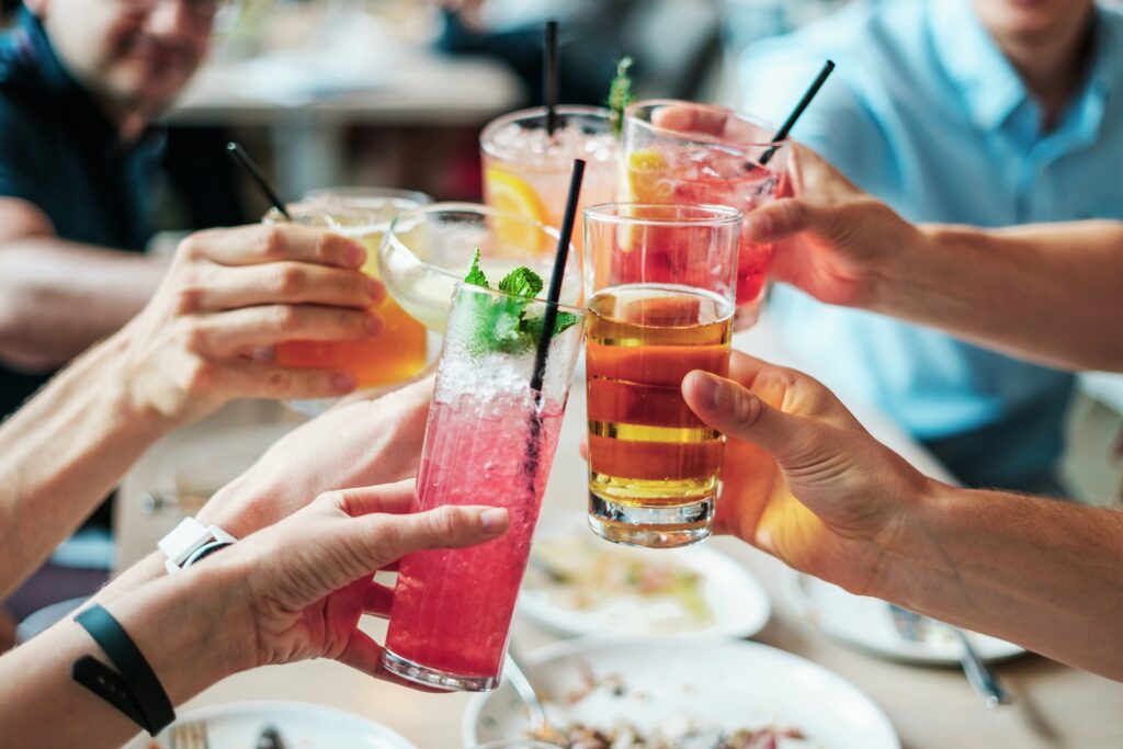 Freunde oder Familie stoßen miteinander am Tisch mit ihren Kaltgetränken an.