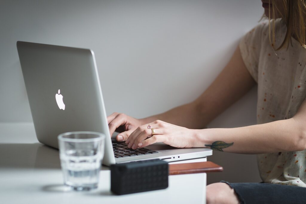 Auf dem Bild ist eine Frau zu sehen, wie sie an ihrem MacBook arbeitet.