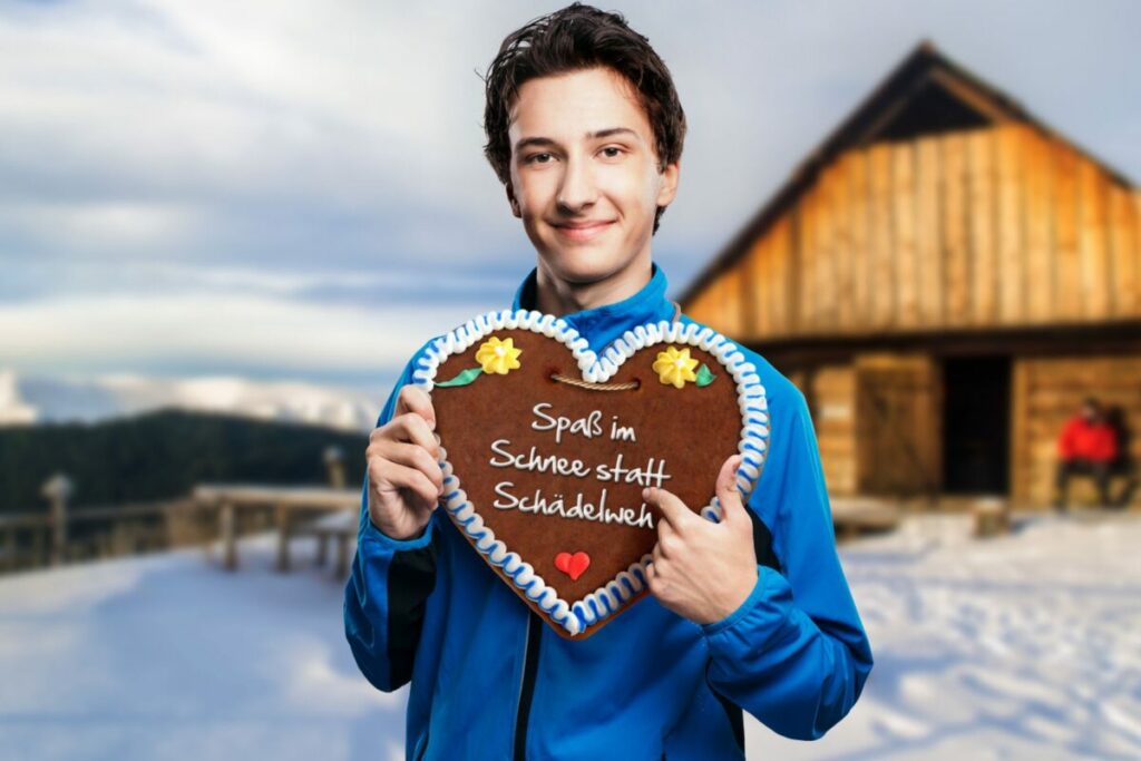 Bub steht im Schnee und hält ein Lebkuchenherz in der Hand