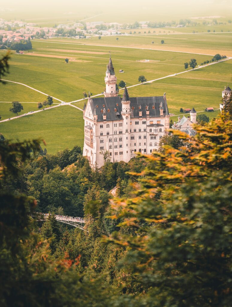 Ein Schloss steht auf einem Hügel, dahinter Felder. Herbstliche Stimmung.