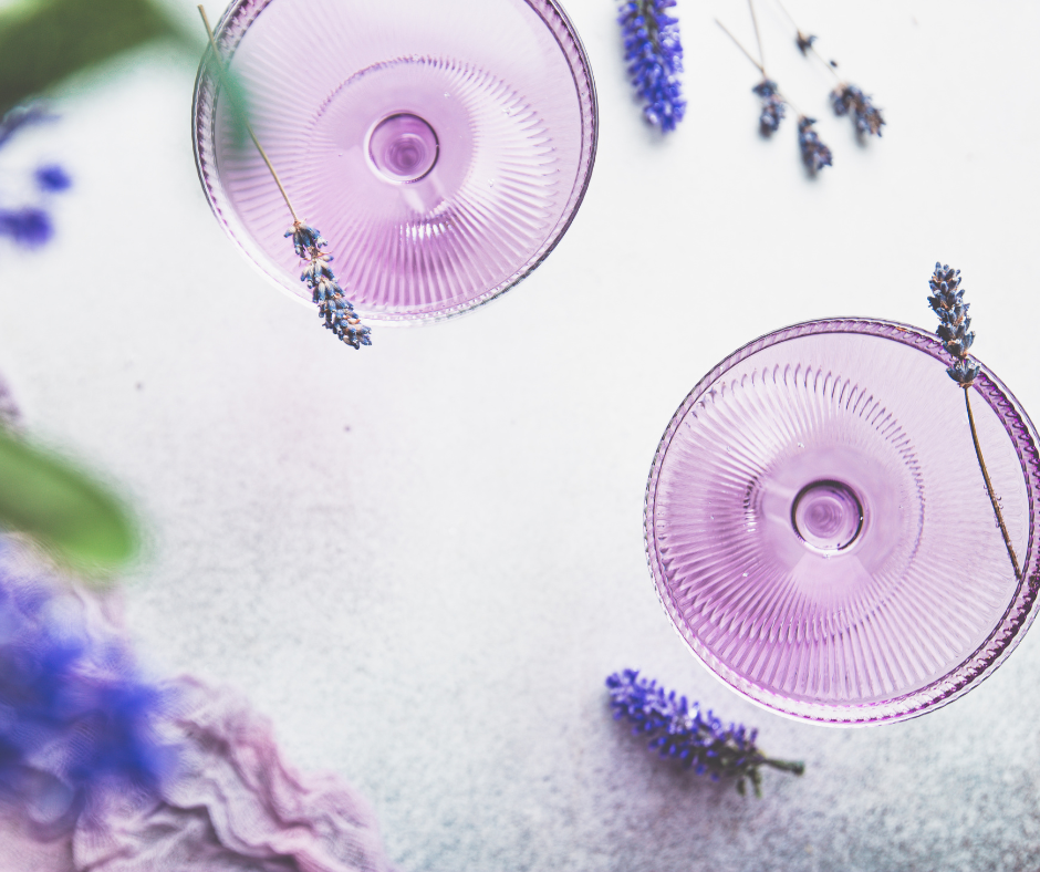 Zwei Cocktailgläser mit violettem Inhalt und Lavendel daneben